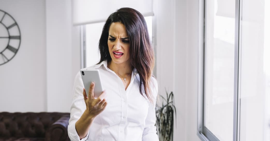 Mulher irritada olhando o celular